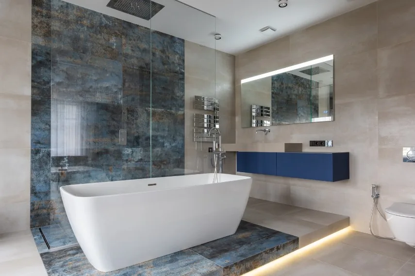 Baño con bañera exenta, iluminación LED indirecta y revestimiento efecto piedra