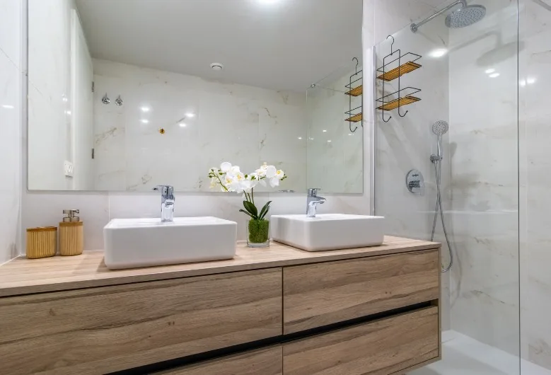 Baño renovado sin obra con doble lavabo sobre mueble de madera y ducha acristalada